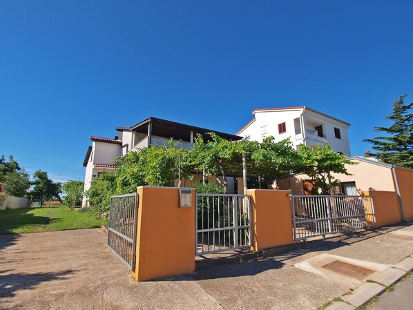 A residential building with a gated entrance, a small garden, and a clear blue sky. - Apartment Jan 325 (Medulin)