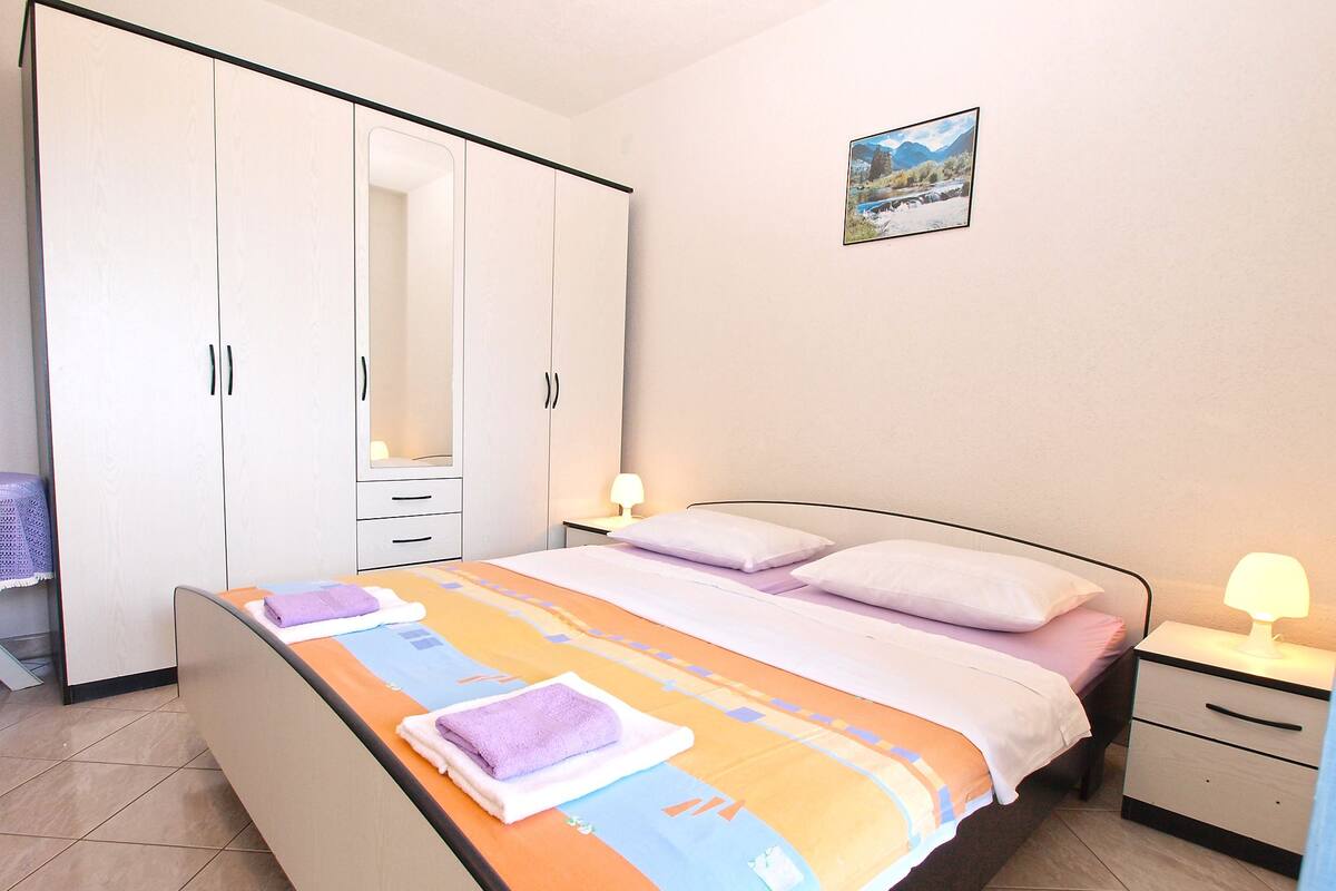A bedroom with a bed, nightstands, a wardrobe, and a framed picture on the wall.