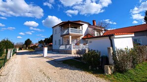 A two-story house with a balcony, a gravel driveway, and a clear blue sky. - Apartment Mila 395 (Medulin)