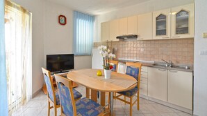 A compact kitchen with a dining area, featuring a TV, a refrigerator, and a sink. - Apartment Mila 395 (Medulin)