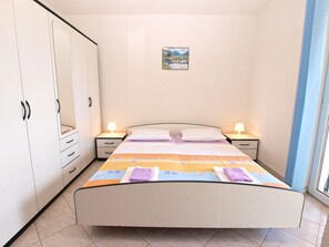 Ein Schlafzimmer mit Bett, Nachttischen, einem Kleiderschrank und einem kleinen Bild an der Wand.