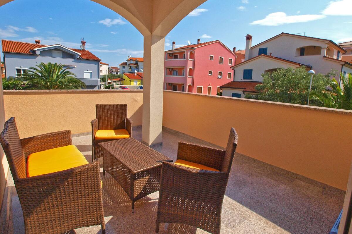 Un balcón con muebles de mimbre y vistas a edificios de colores.
