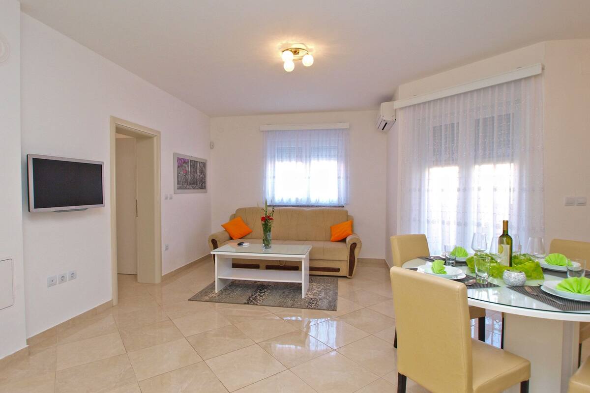Sala de estar con sofá, mesa de centro y mesa de comedor dispuesta para una comida.