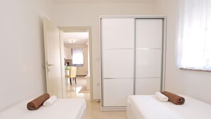 Ein Hotelzimmer mit zwei Betten, einem Schiebetürenschrank und Blick auf die Küche und den Speisebereich.
