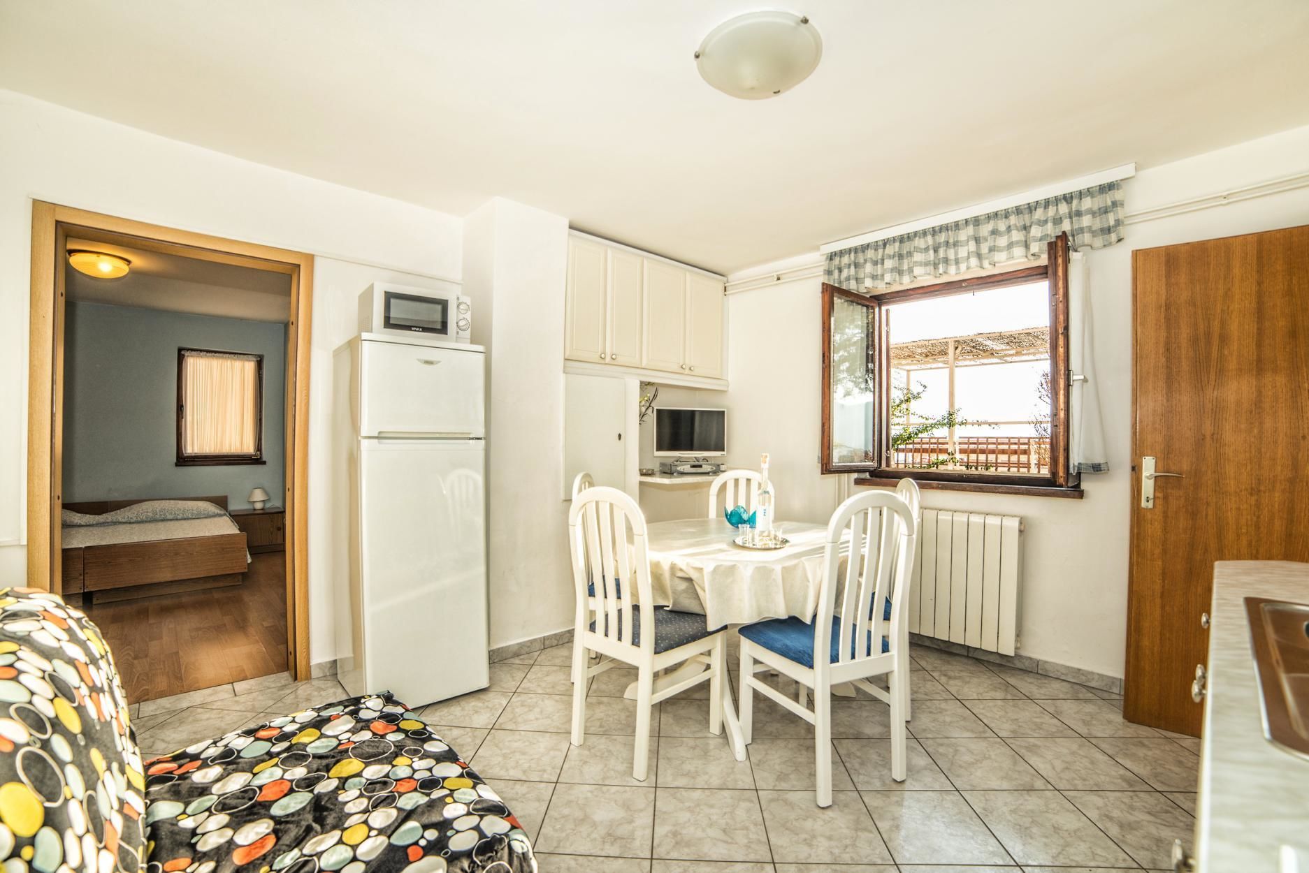 A compact kitchen with a dining area, a microwave, a refrigerator, and a window with a view.