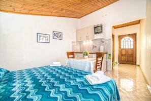 Une chambre avec un lit, une petite table et un coin cuisine.