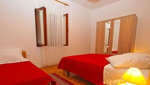 Un dormitorio con dos camas, un armario de madera y una mesita de noche con una lámpara.
