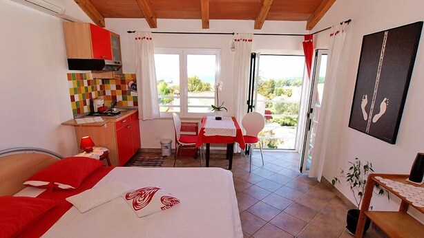 Un dormitorio con cama, una kitchenette pequeña y una zona de comedor con mesa y sillas.