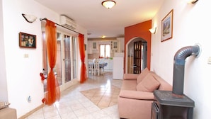 Una sala de estar con sofá, chimenea y una cocina al fondo.