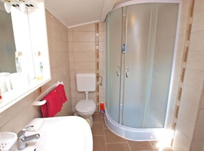 A bathroom with a white sink, a toilet, a shower with frosted glass doors, and a mirror above the sink. - Apartment Franko 749 (Pula)