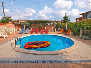 A swimming pool with a red inflatable raft, surrounded by lounge chairs and a stone wall. - Apartment Franko 749 (Pula)