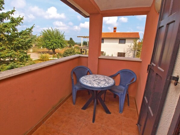 A balcony with two blue plastic chairs and a small round table, overlooking a residential area with trees and houses. - Apartment Franko 749 (Pula)