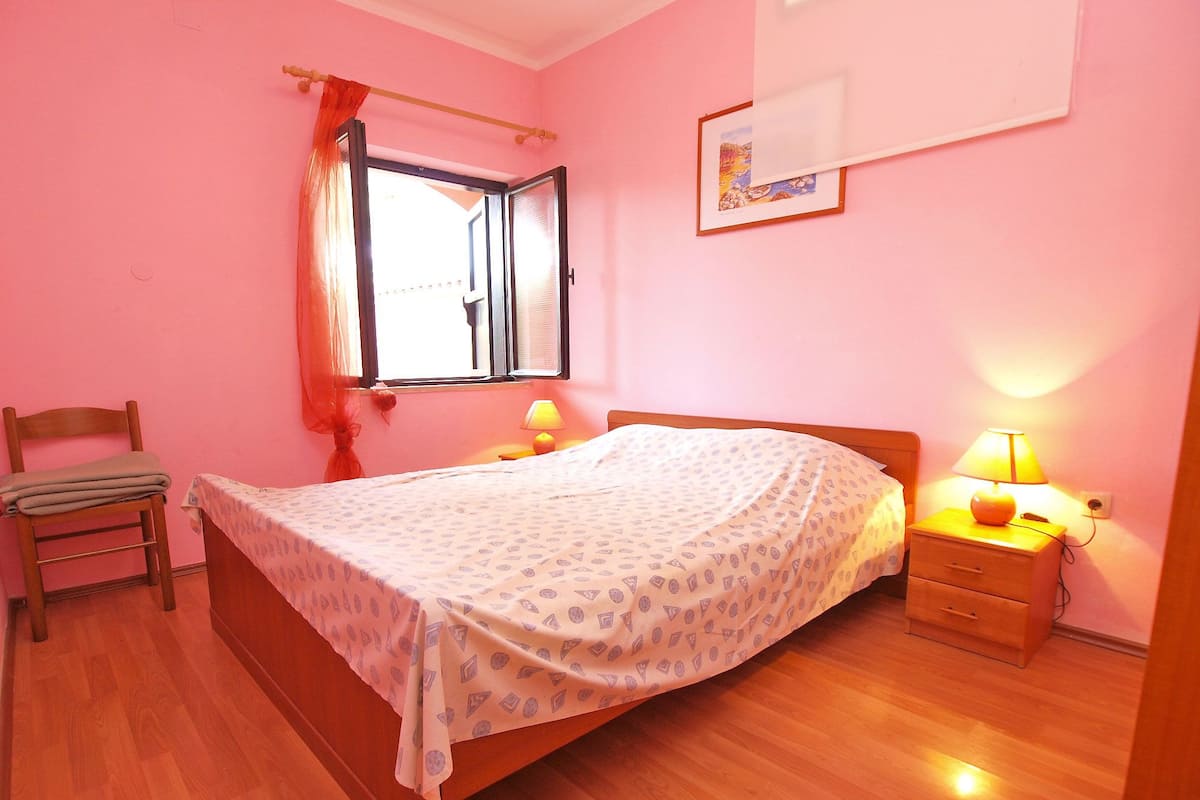 Une chambre à coucher avec un lit, des tables de chevet, une chaise et une fenêtre avec des rideaux.