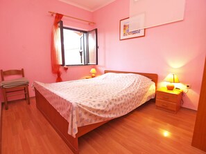 A bedroom with a bed, bedside tables, a chair, and a window with curtains. - Apartment Franko 749 (Pula)