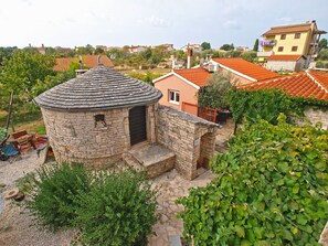 A stone building with a circular roof, surrounded by greenery and residential houses with red-tiled roofs. - Apartment Franko 749 (Pula)