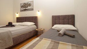 Une chambre d’hôtel avec deux lits, une petite table ronde, un tableau au mur et un tapis à carreaux.