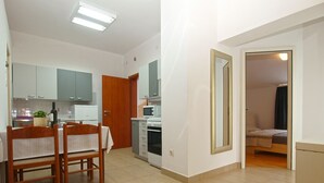 Un espace de vie compact comprenant un coin repas, une kitchenette et une chambre.