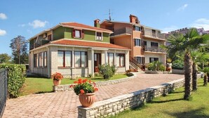 Une maison à deux étages avec une façade en briques, de grandes fenêtres et une allée pavée.