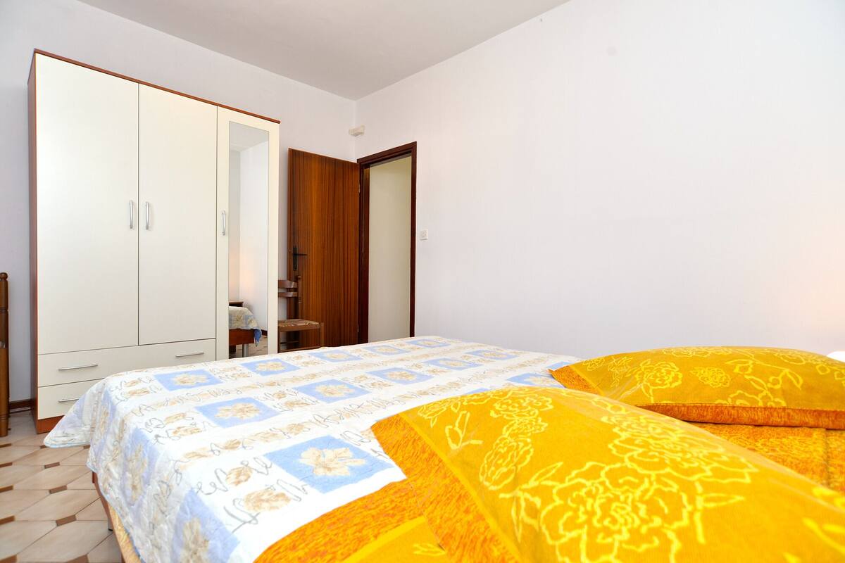 A bedroom with a bed, a wardrobe, and a door leading to another room.