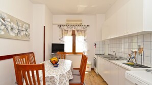 Une cuisine compacte avec des meubles blancs, un lave-vaisselle et un coin repas comprenant une table et des chaises.