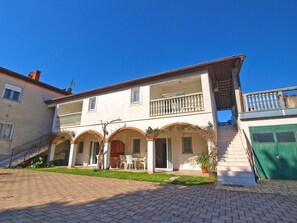 Ein zweistöckiges Gebäude mit Balkon, Treppe und grünem Tor.