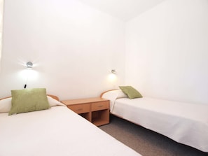 A twin room with two single beds, each with a green pillow, a wooden nightstand, and a wall-mounted lamp. - Apartment Jozefina 1261 (Medulin)