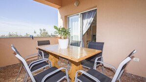 A balcony with a wooden table and four chairs, a potted plant, and a sliding glass door. - Apartment Mirsad 1282 (Fazana)