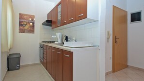 A compact kitchen with wooden cabinets, a gas stove, a sink, and a refrigerator. - Apartment Mirsad 1282 (Fazana)