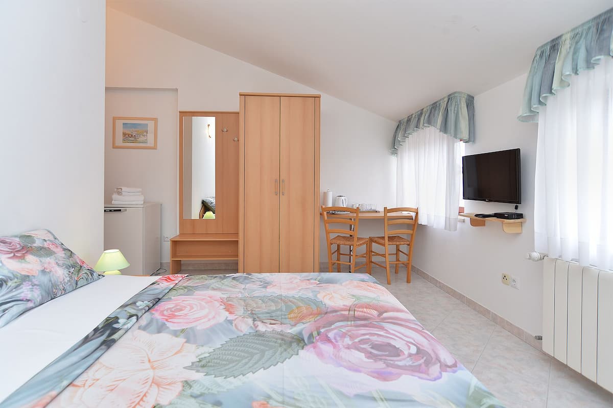 Une chambre à coucher comprenant un lit, un bureau, une chaise, une télévision et une armoire.