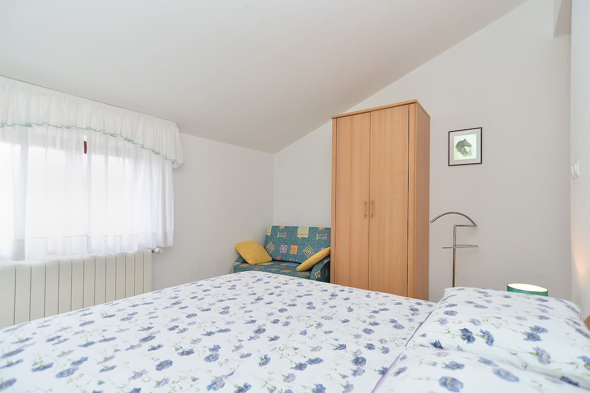 Une chambre à coucher avec un lit, une armoire, une chaise, un radiateur et un tableau accroché au mur.
