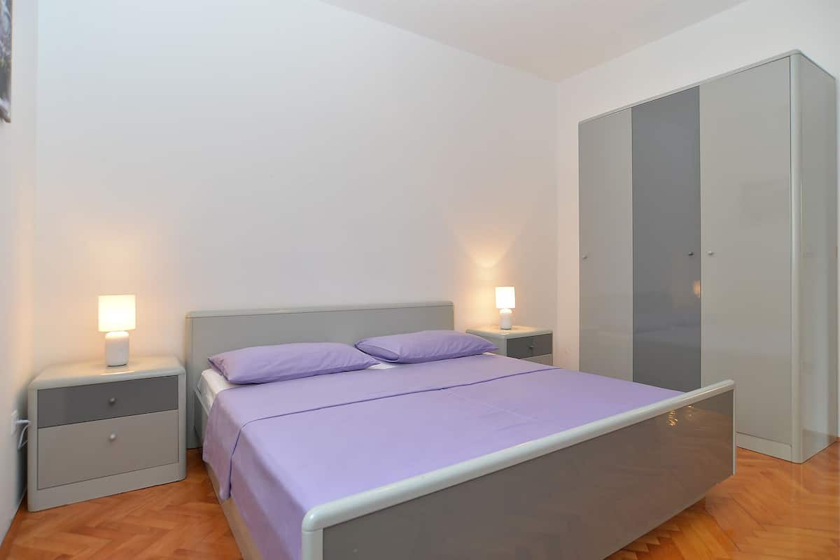 Une chambre à coucher comprenant un lit, des tables de chevet, une armoire et une lampe fixée au mur.