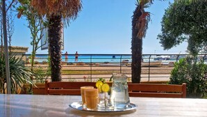A table with drinks and a pitcher, overlooking a beach with palm trees and a clear sky. - Apartment Vlado 1405 (Vodnjan)