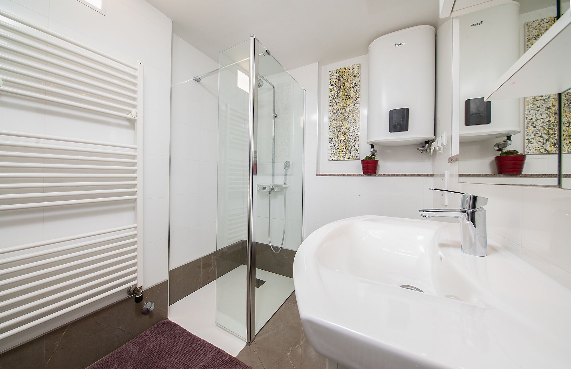 A modern bathroom with a glass shower enclosure, a white sink, and a mirror with a decorative backsplash.
