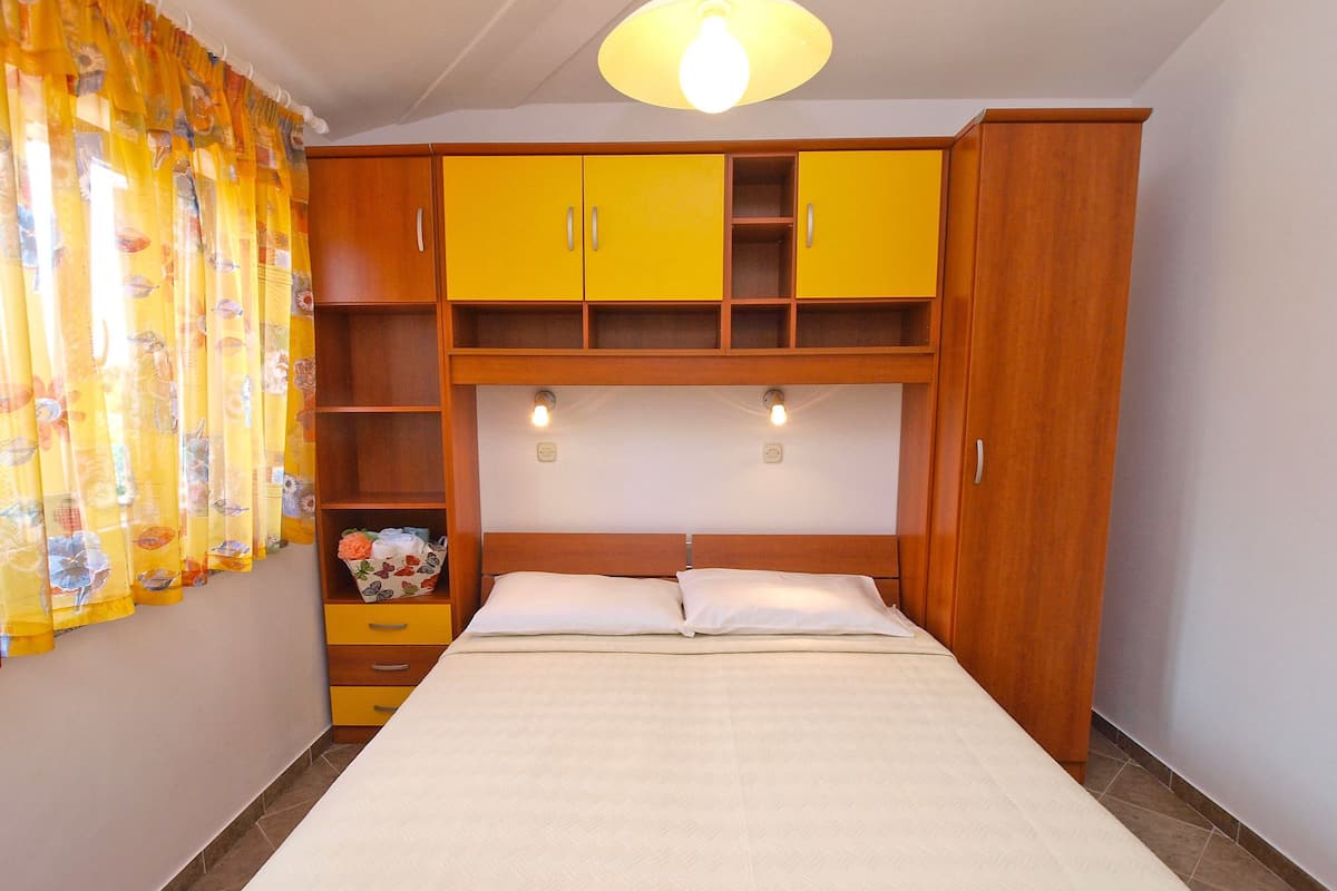 Un dormitorio con cama, armarios de madera y una cortina.