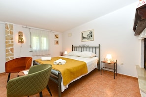 Une chambre d’hôtel avec un lit, une chaise, une table de chevet, une lampe et un tableau au mur.