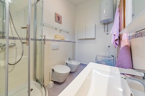 Une salle de bain équipée d’une douche à parois de verre, de toilettes, d’un bidet, d’un lavabo et d’un chauffe-eau Bosch.