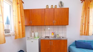 Een kleine keuken met houten kastjes, een koelkast en een wastafel.