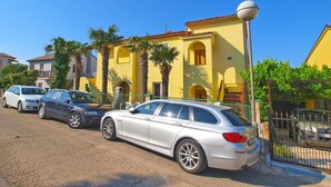 A yellow building with a red-tiled roof, parked cars, and a street lamp. - Apartment Gey 671 (Medulin)