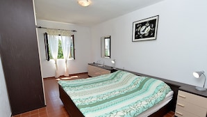 A bedroom with a bed, a dresser, a mirror, and a window with curtains. - Apartment Gey 671 (Medulin)