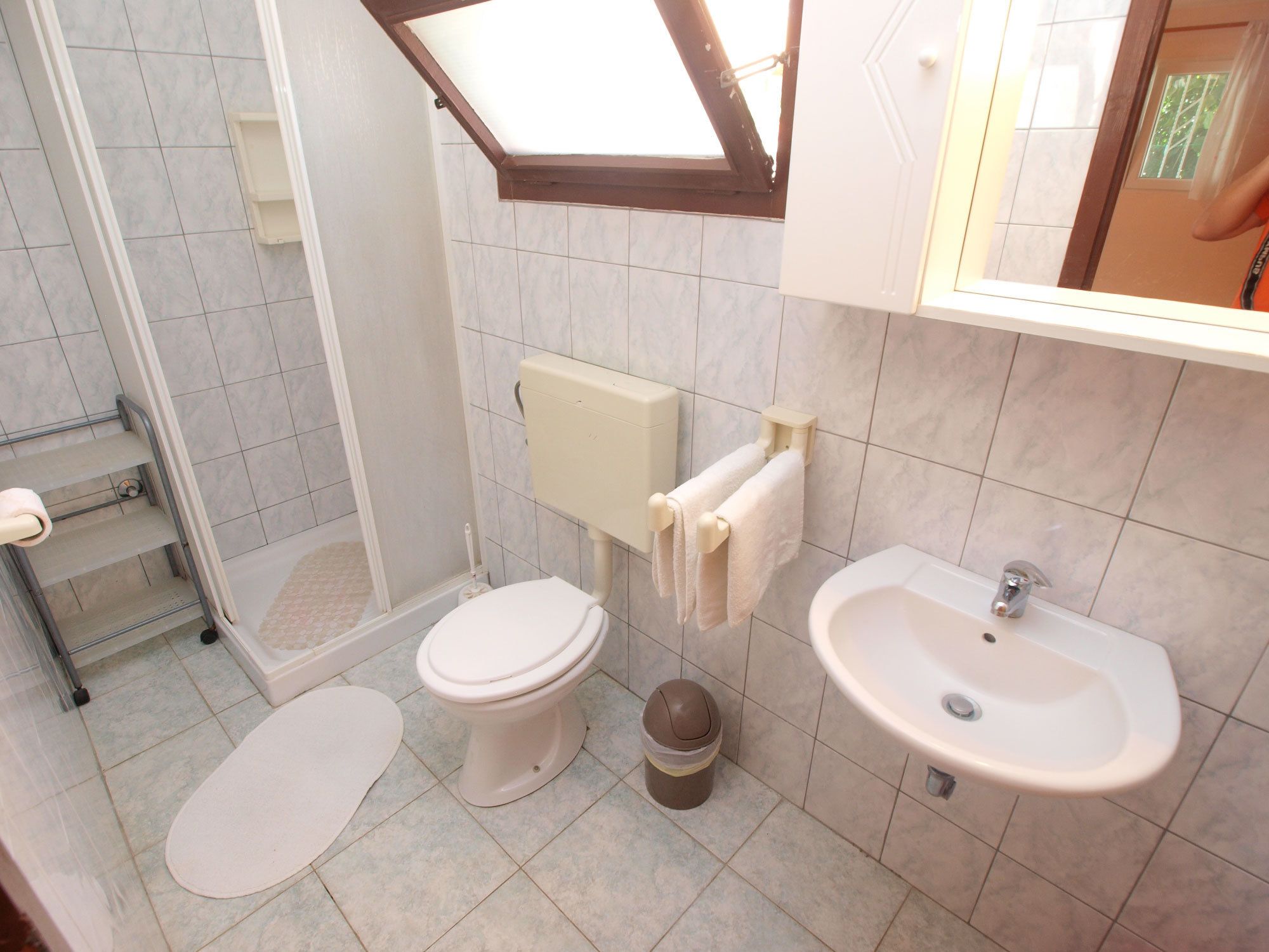 Een badkamer met toilet, bidet, wastafel en een klein raam.