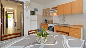 Una cocina compacta con armarios de madera, microondas, estufa y refrigerador.