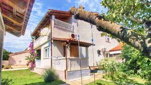 Una casa de dos pisos con balcón, columpio y jardín.