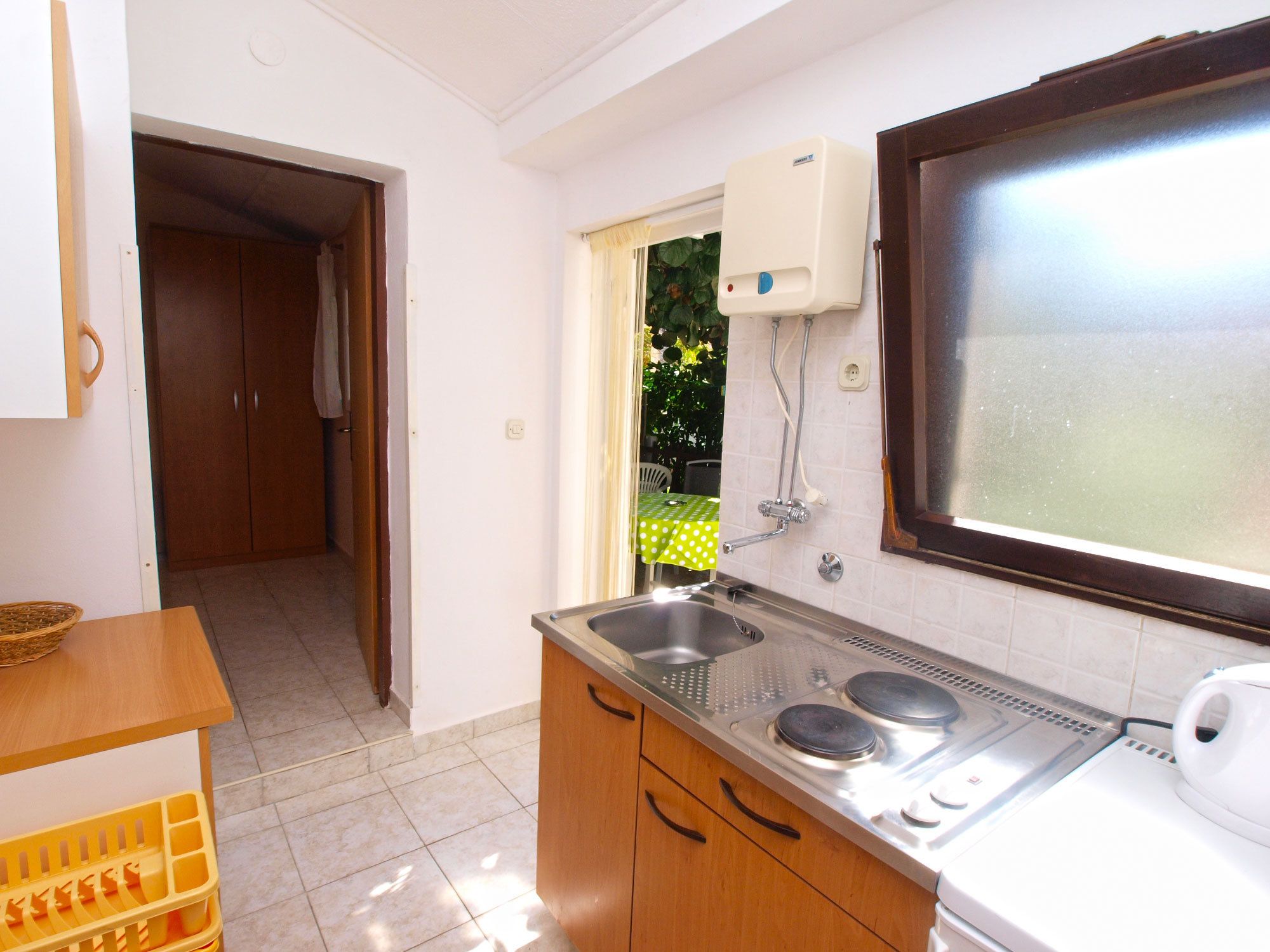 A kitchen with a sink, stove, and a window with a view of greenery outside.