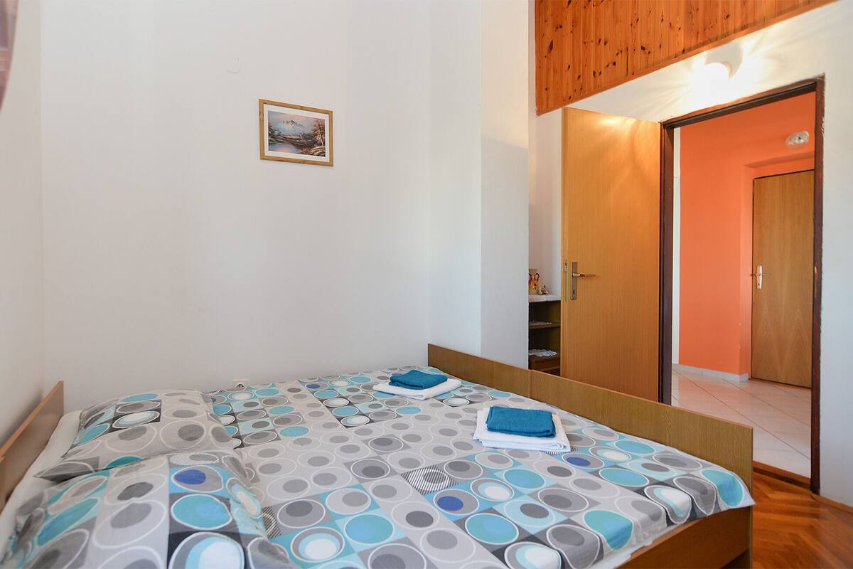 A bedroom with a bed, a small framed picture on the wall, and a wooden door.