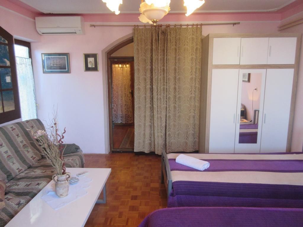 A room with a sofa, a bed, a small table with a vase, and a wardrobe.