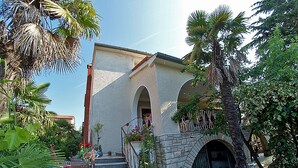 A building with a stone staircase leading to an arched entrance, surrounded by lush greenery and palm trees. - Apartment Ivanka 378 (Rovinj)