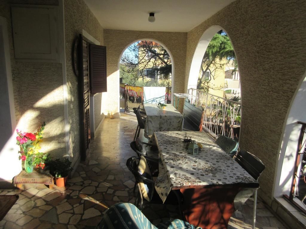 A sunlit patio with a table and chairs, stone flooring, and a view through an archway.