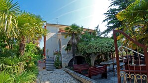 A courtyard with stone flooring, a bench, and a building with a tiled roof. - Apartment Ivanka 378 (Rovinj)