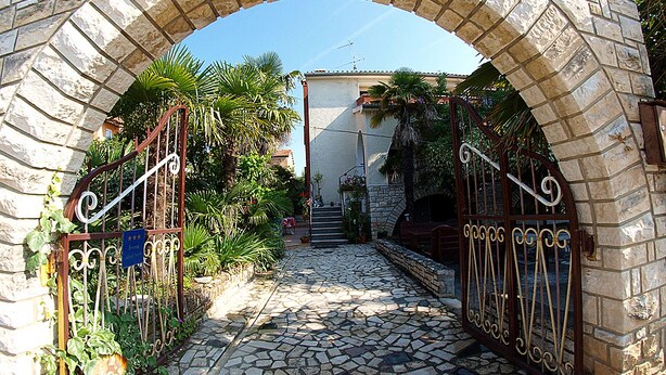A stone archway leading to a building with a tiled pathway and metal gates. - Apartment Ivanka 378 (Rovinj)