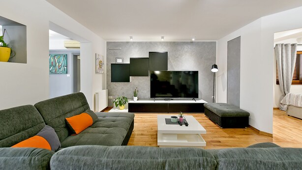 Una sala de estar moderna con un sofá gris, una mesa de centro y un televisor de pantalla plana.